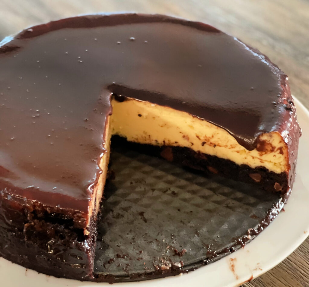chocolate fudge drizzled on top of cheesecake with a brownie crust