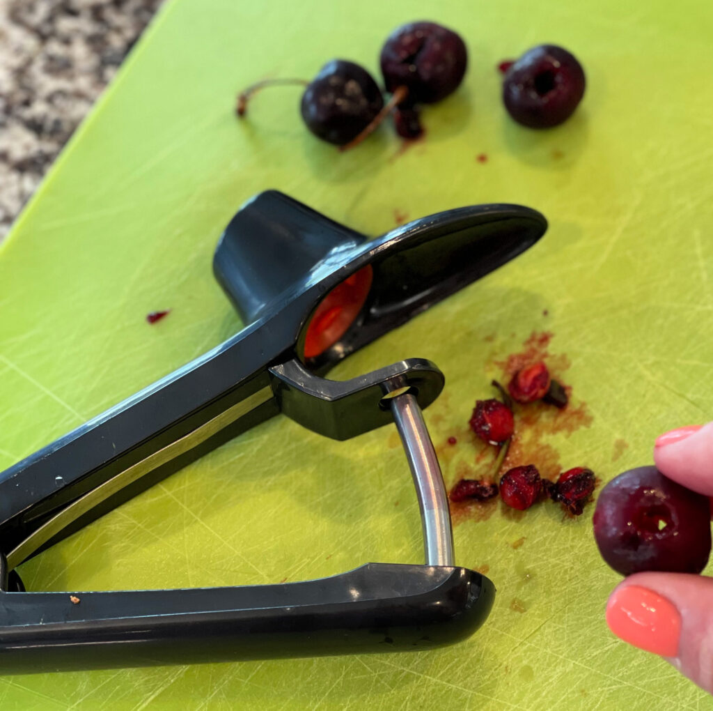 a cherry pitter taking the seed out of a cherry