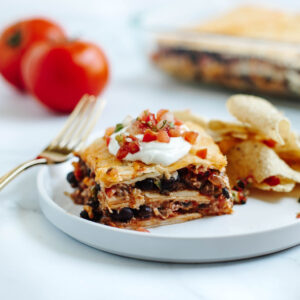 a white dinner plate with Taco Lasagna and tortilla chips.
