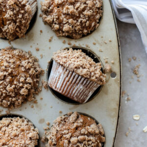 a crumb topped muffin on its side in a muffin tin.