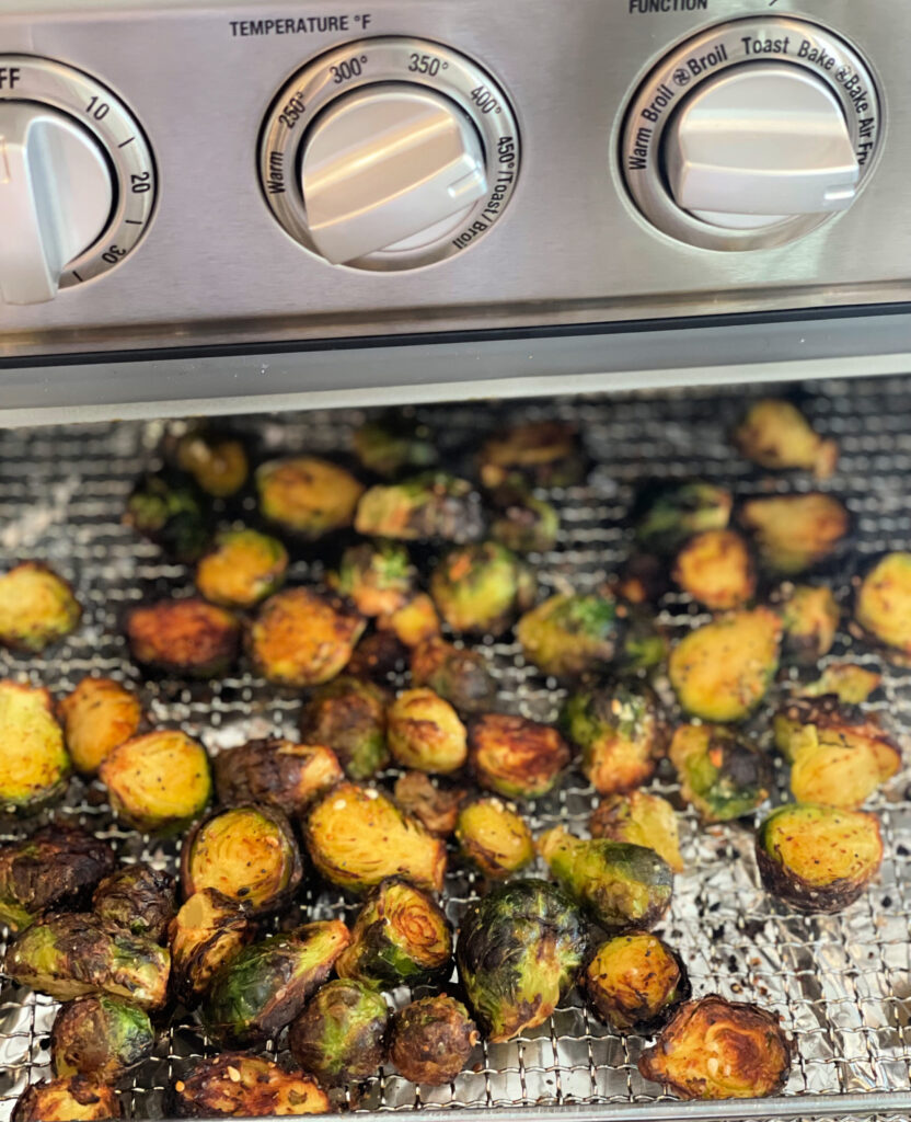 Seasoned brussel sprouts in an air fryer basket.