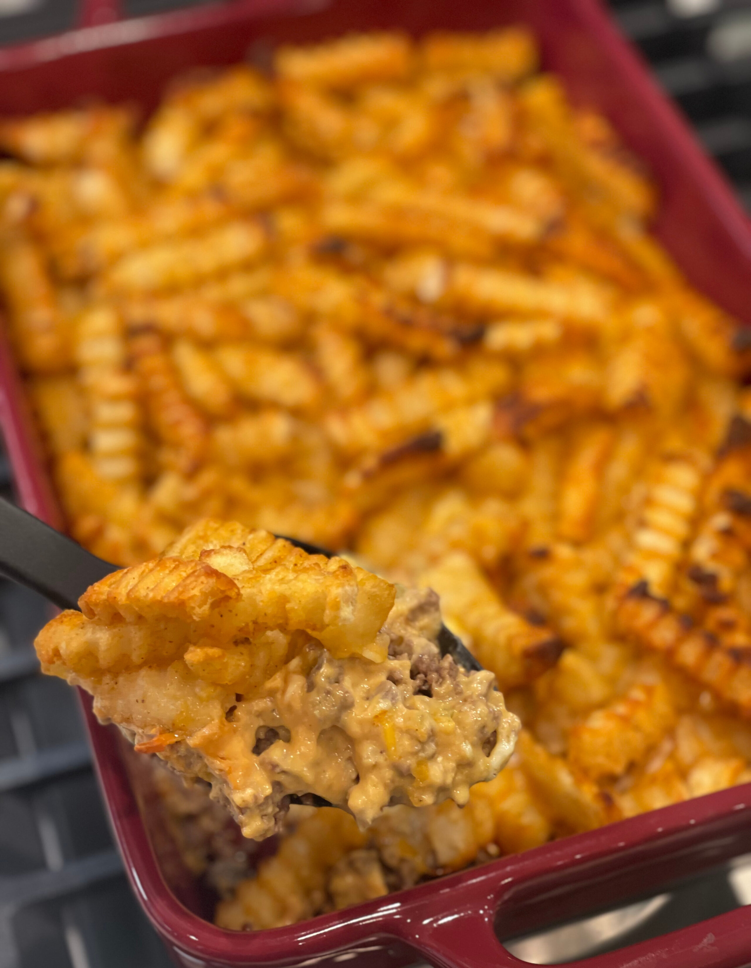 a casserole with crispy French fries and a ground beef mixture coated in ketchup and mustard.