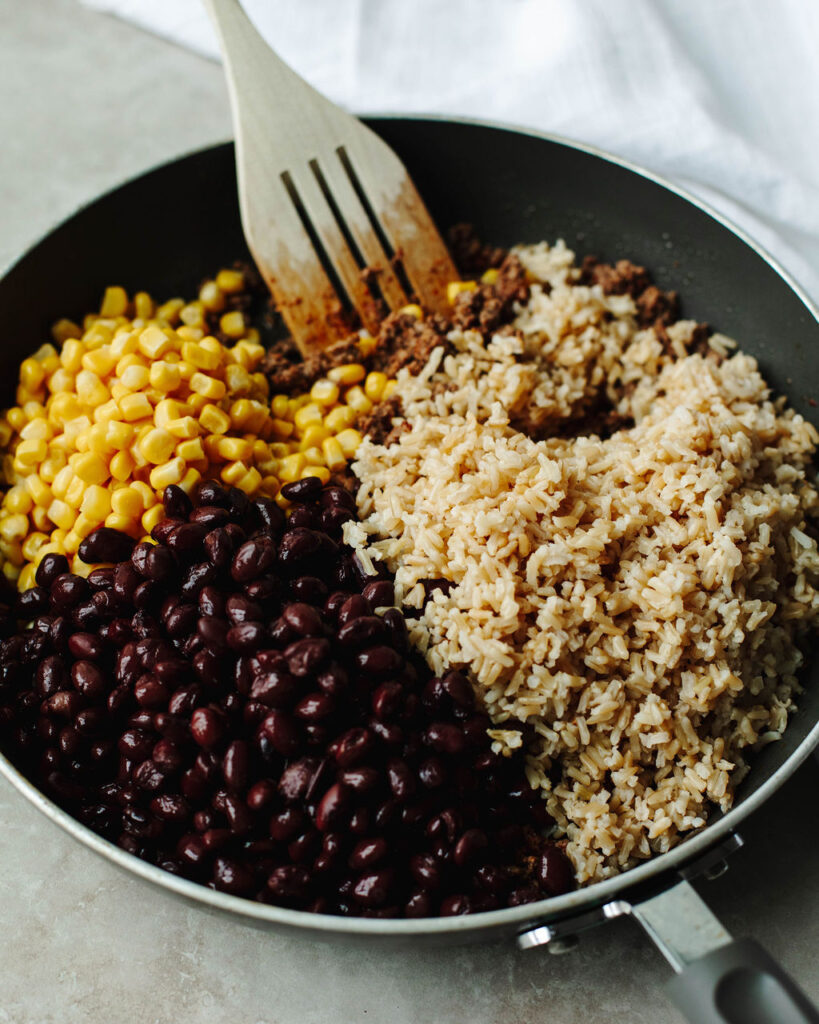 ground beef, rice, corn, and black beans in a skillet.