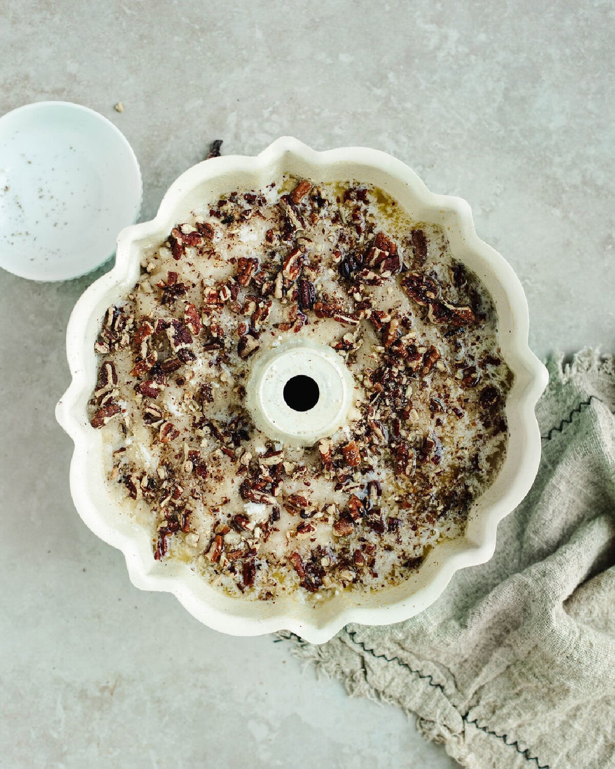 melted butter and chopped nuts sprinkled on top of Bisquick and apple pie filling in a bundt pan.