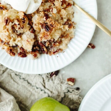 Apple Cobbler with Bisquick served in a white bowl with vanilla ice cream.