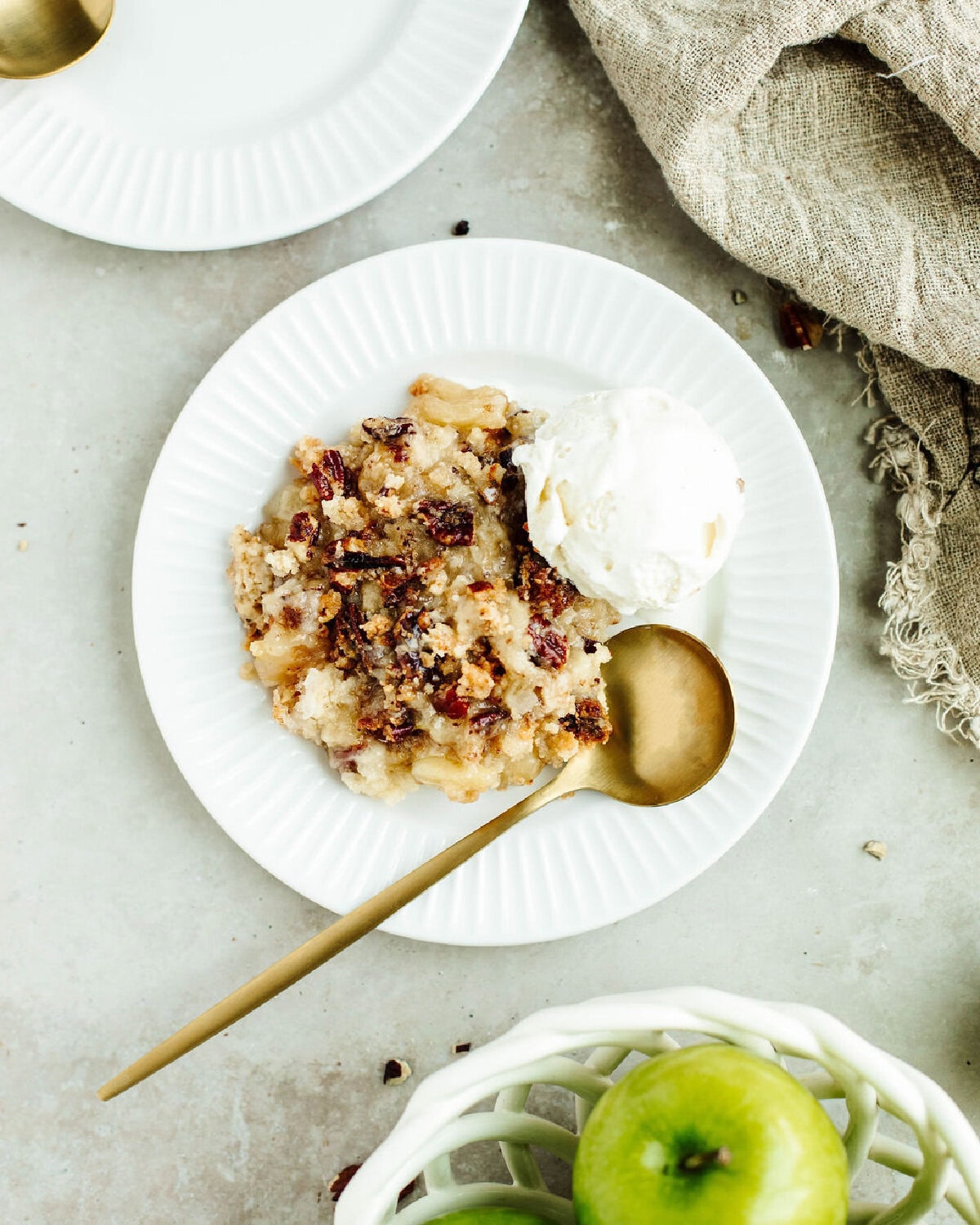 Easy Bisquick apple cobbler served in a bowl with a scoop of vanilla ice cream and caramel drizzle.
