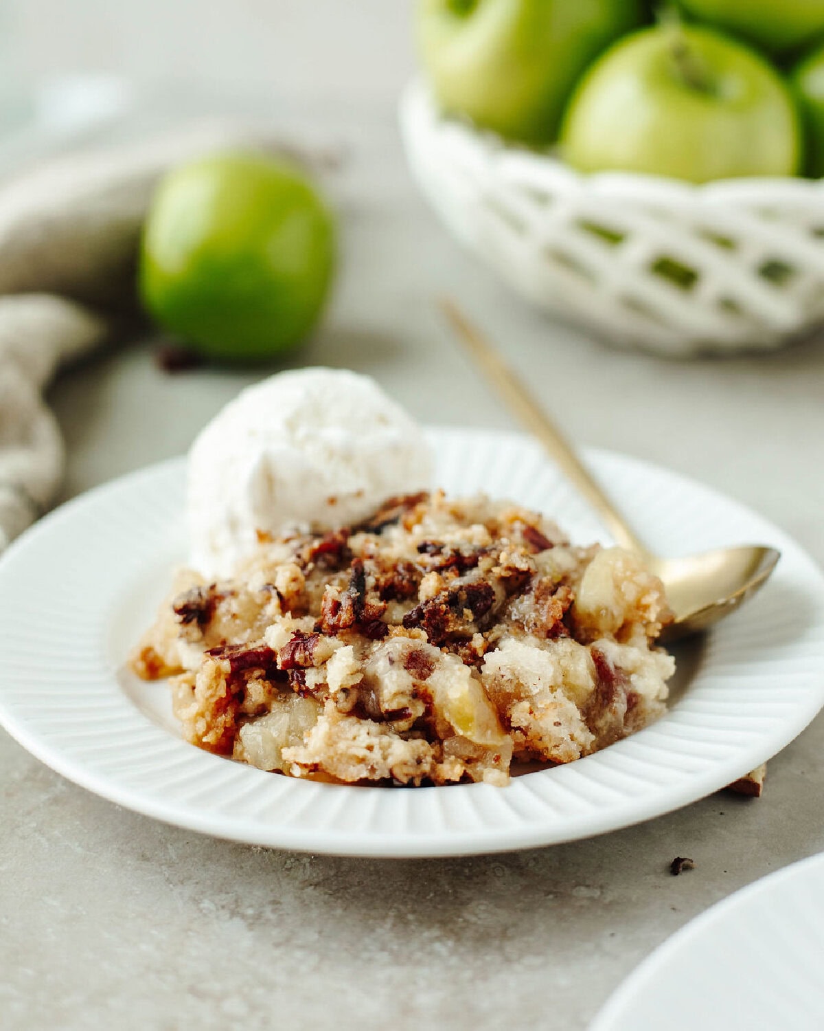 scooped apple cobbler with bisquick served in a white bowl with ice-cream.