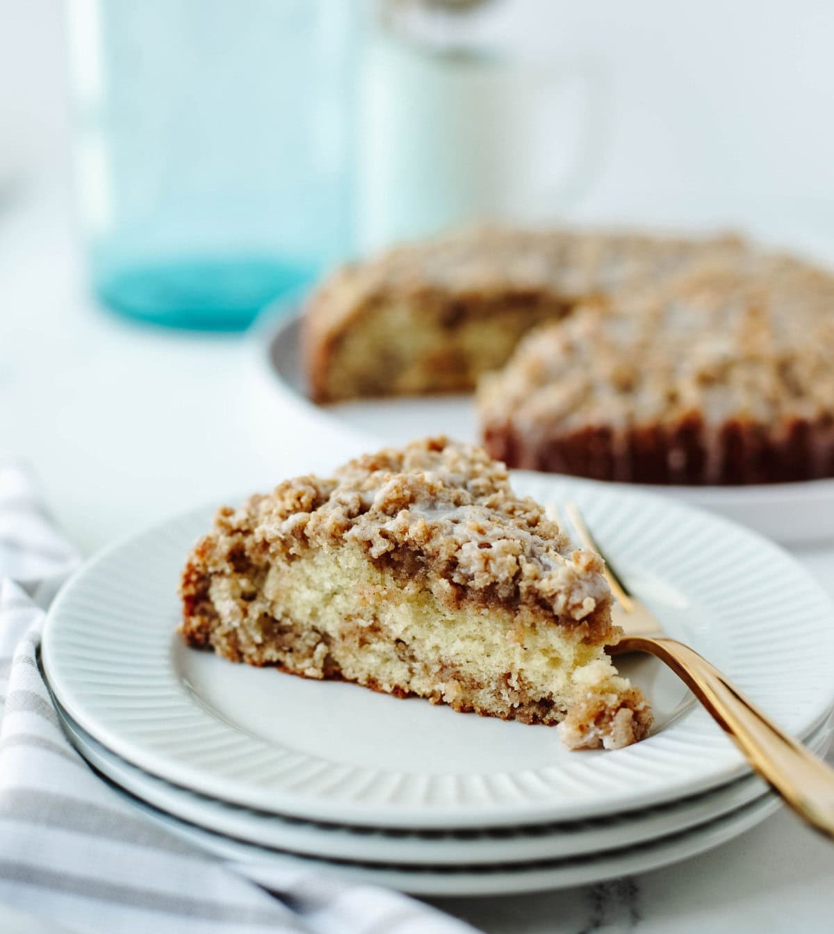 Slice of Apple Cinnamon Crumb Cake with golden crumb topping and fresh apple chunks, served on a white plate.
