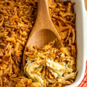 a wooden spoon scooping a serving of hearty casserole.