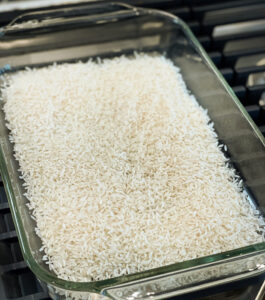 uncooked white rice layered on the bottom of a casserole pan