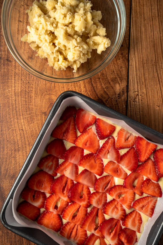 fresh strawberries layered on top of vanilla coffee cake with a buttery crumb topping