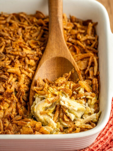 a wooden spoon scooping a serving of hearty casserole.
