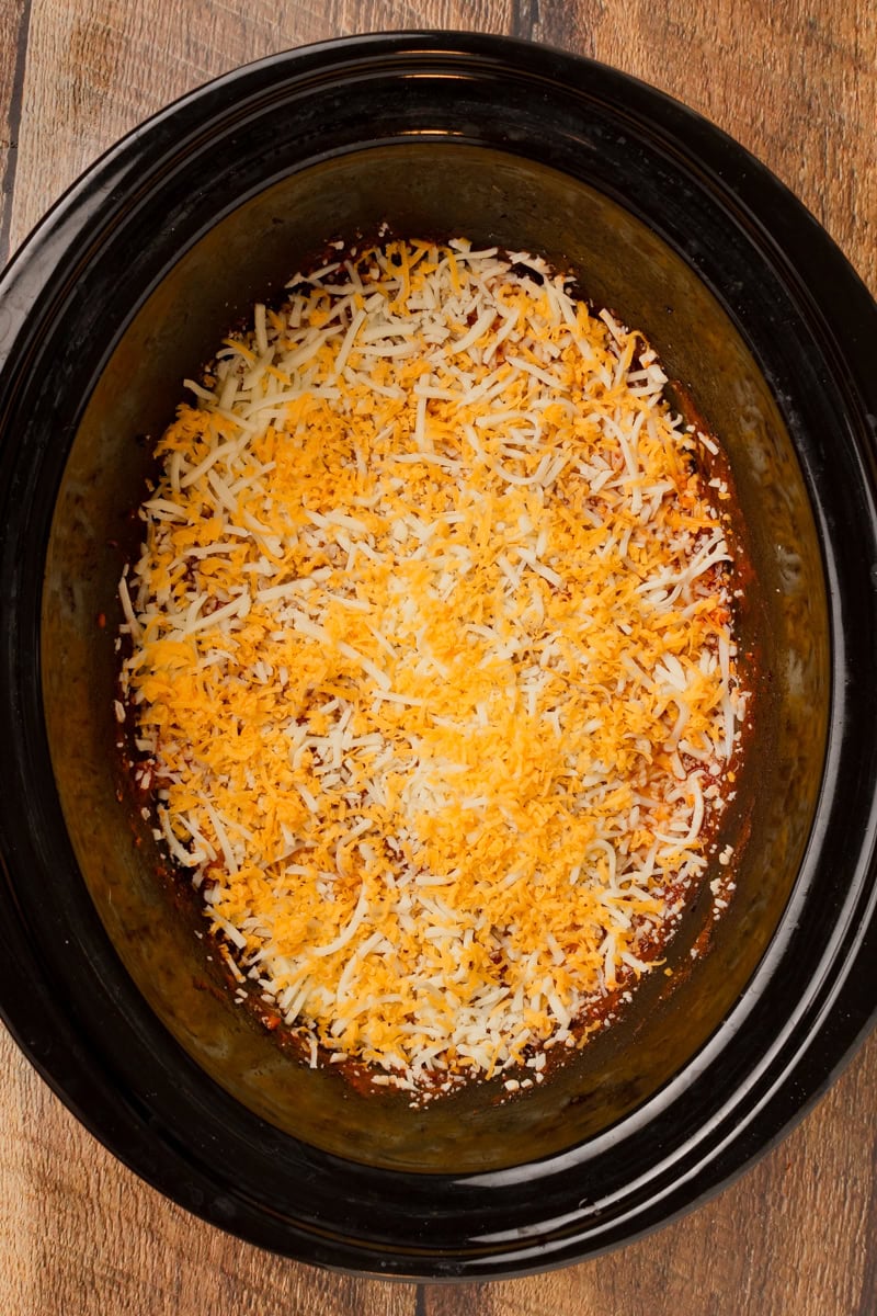 shredded Mozzarella and Cheddar cheese sprinkled on top of the cooked tortellini in a crockpot.