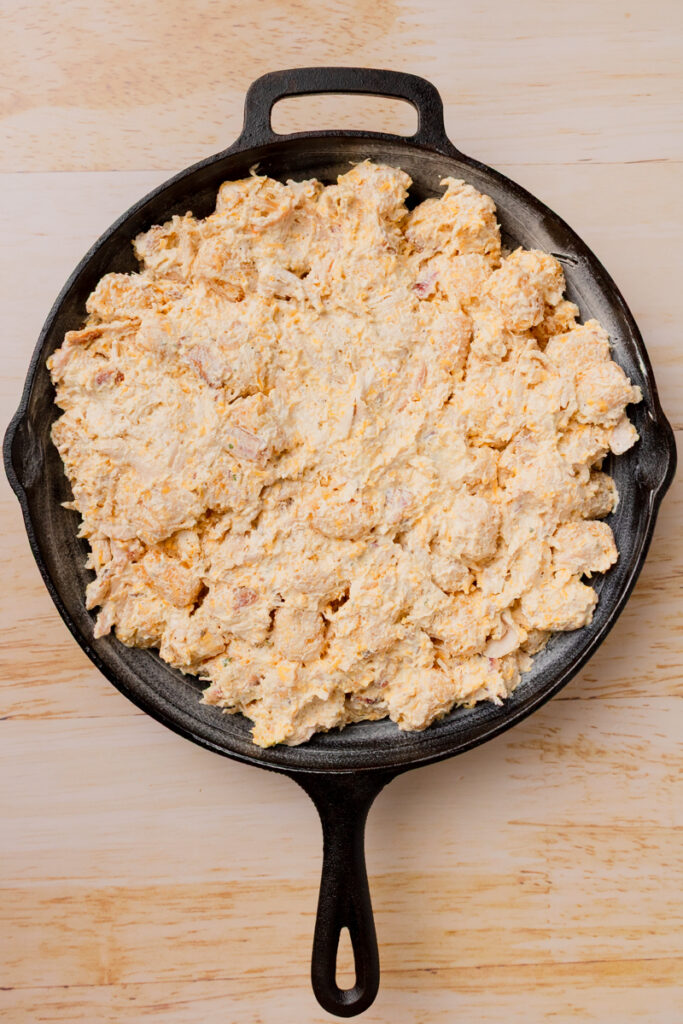 a shredded chicken recipe with frozen potatoes in a cast iron ready to bake.