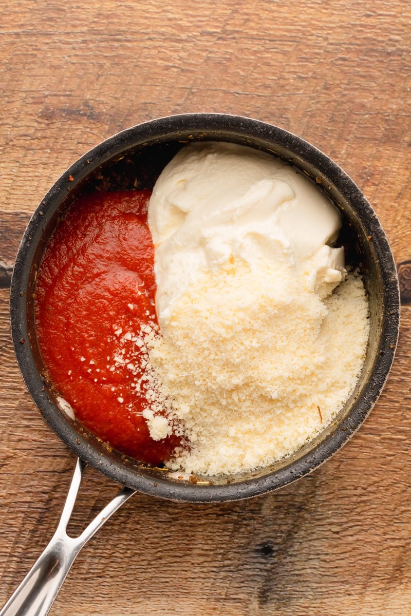 spaghetti sauce, ricotta, mozzarella, and parmesan combined with cooked ground beef in a skillet.