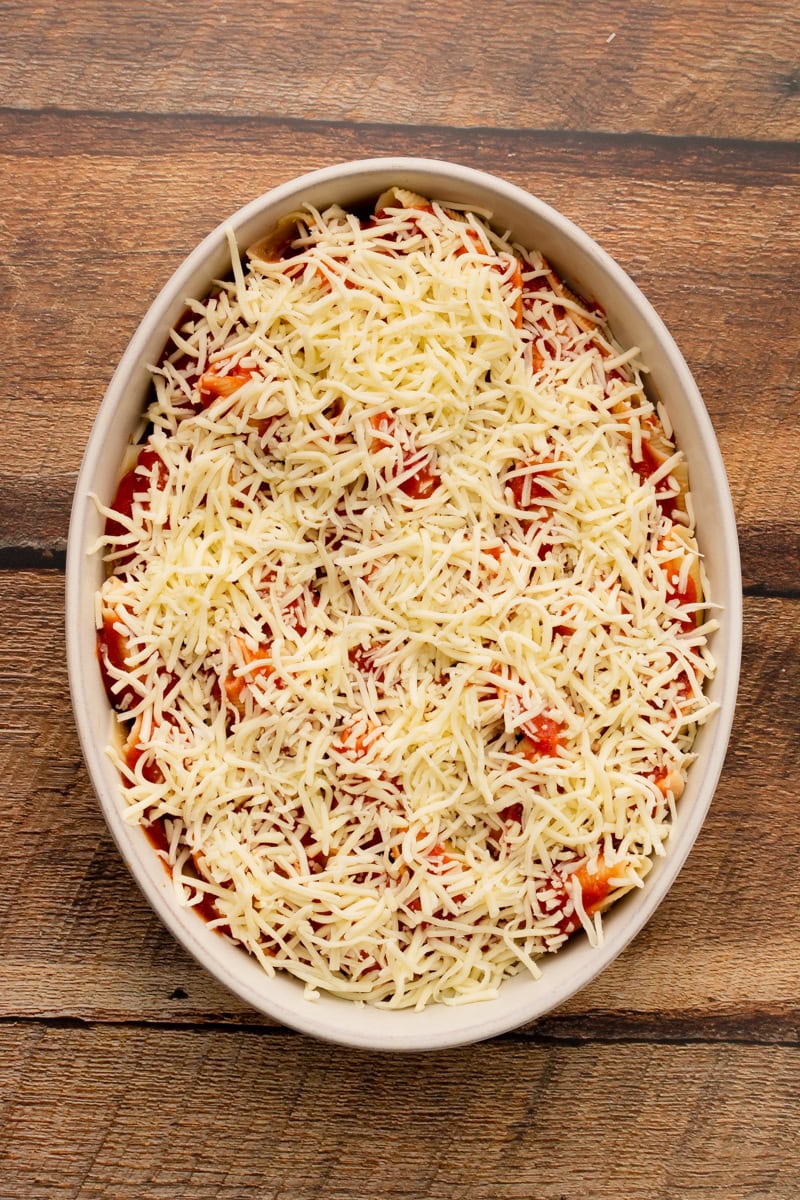 shredded mozzarella cheese on top of lasagna stuffed shells.
