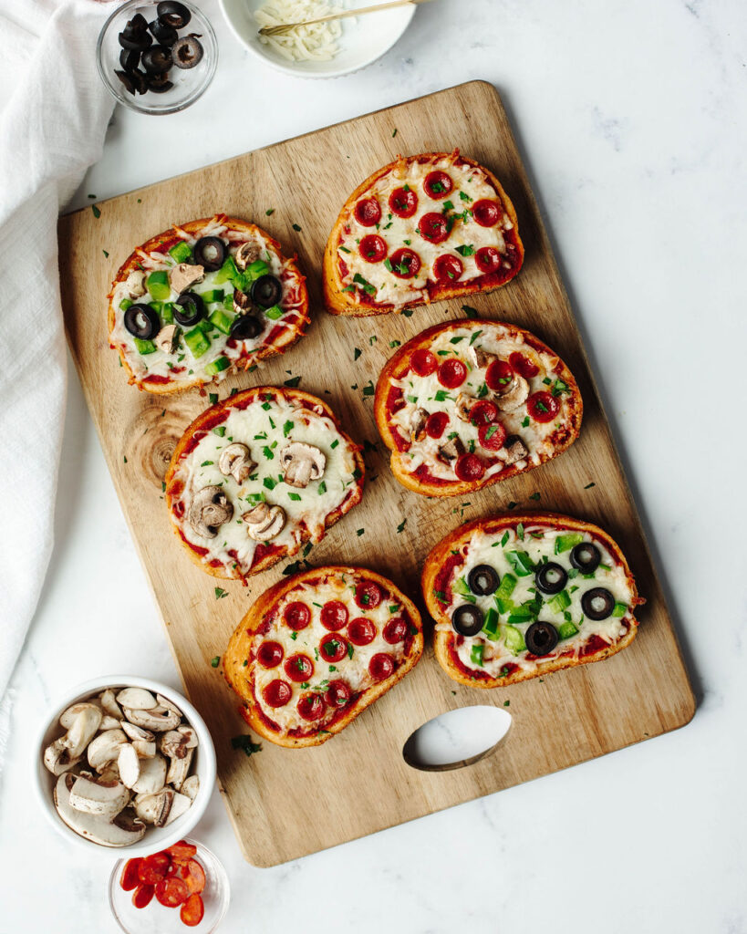 mini pizzas made from texas toast on a wood cutting board.