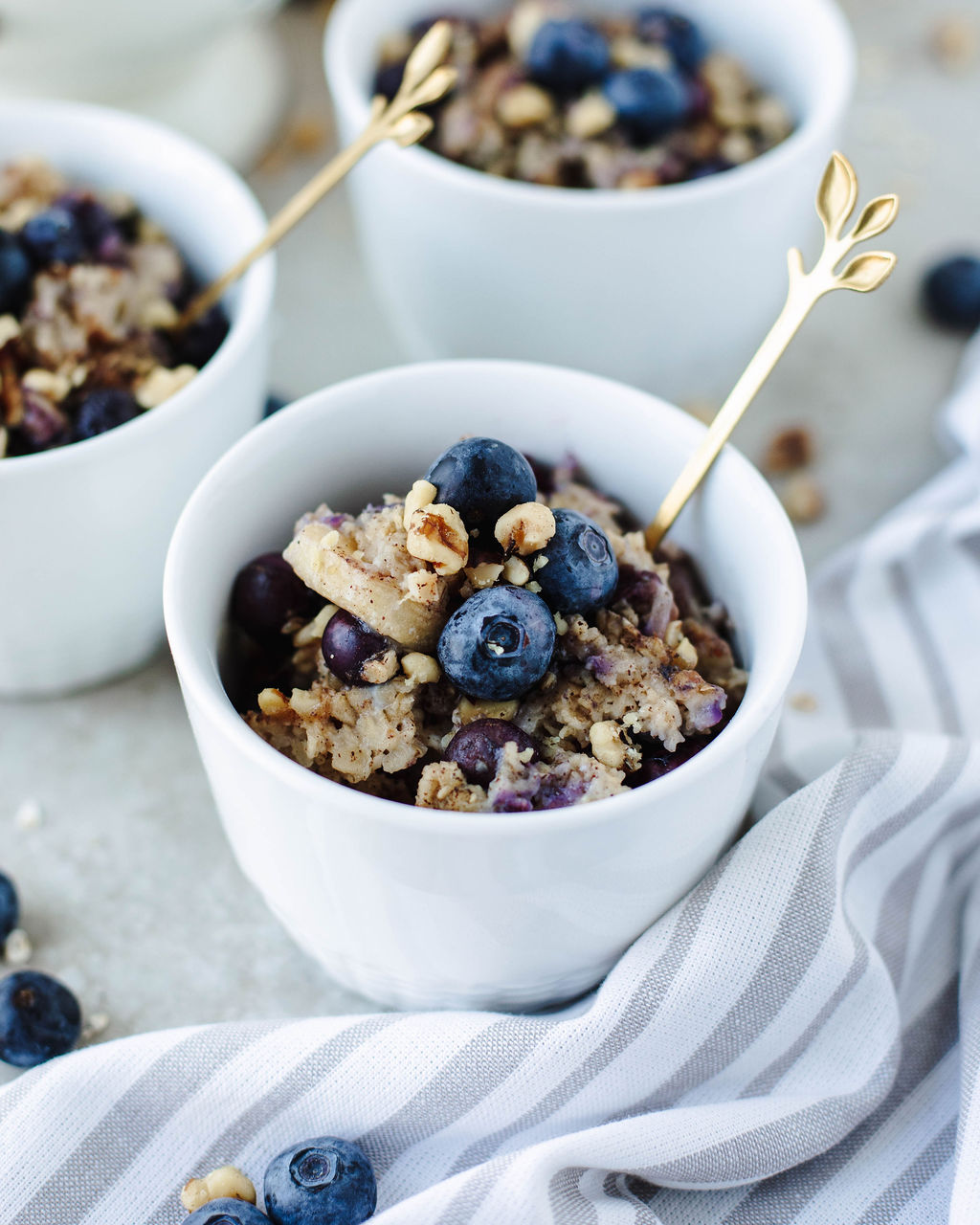 Healthy baked oatmeal with oats, banana slices, and juicy blueberries in serving bowls.
