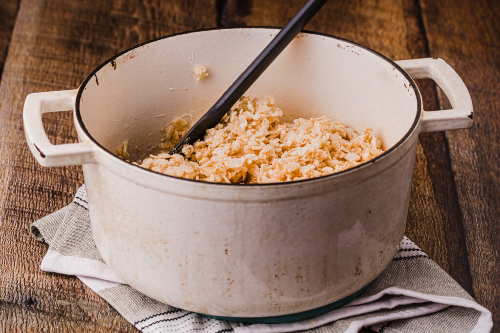 melted marshmallows coating rice krispy cereal in a pot