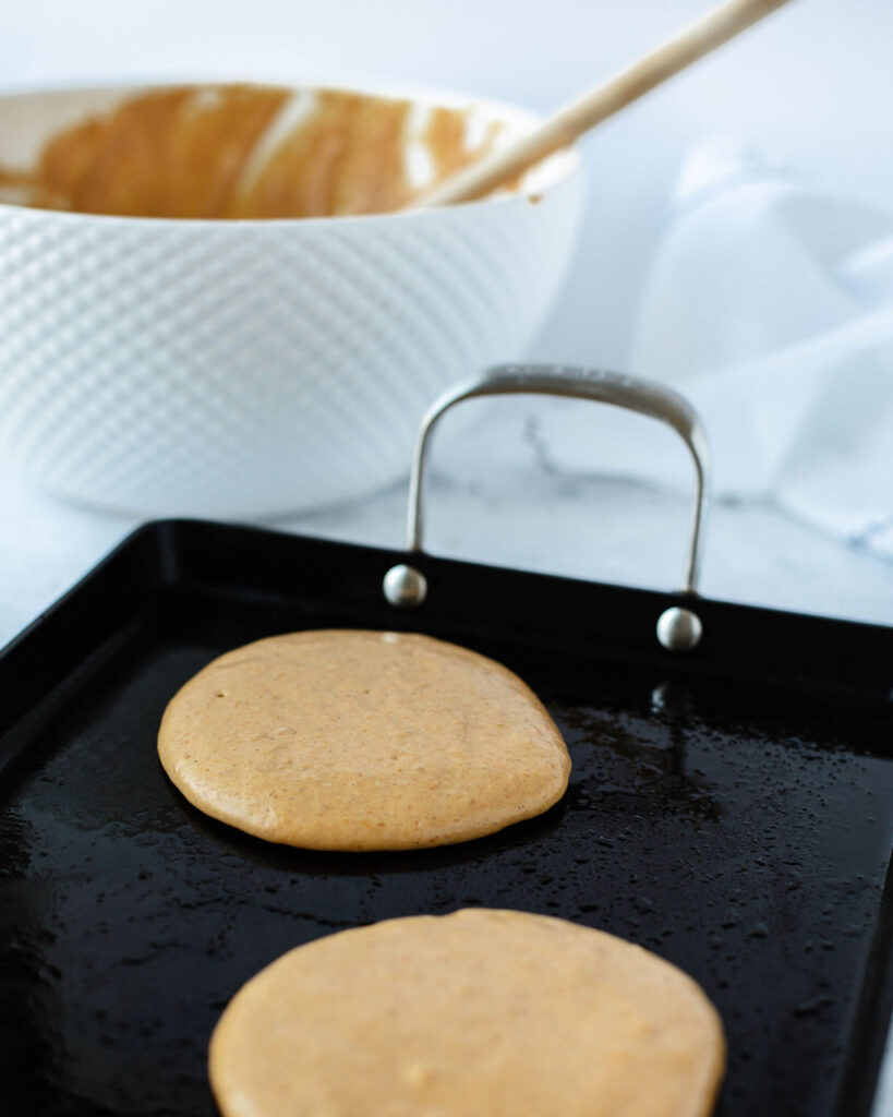 pumpkin batter poured onto a griddle to make pancakes.
