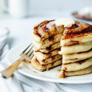 a fluffy breakfast treat served with syrup and butter on a plate.