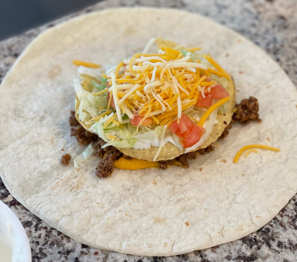 flour tortilla with taco meat, cheese, lettuce, and tomatoes