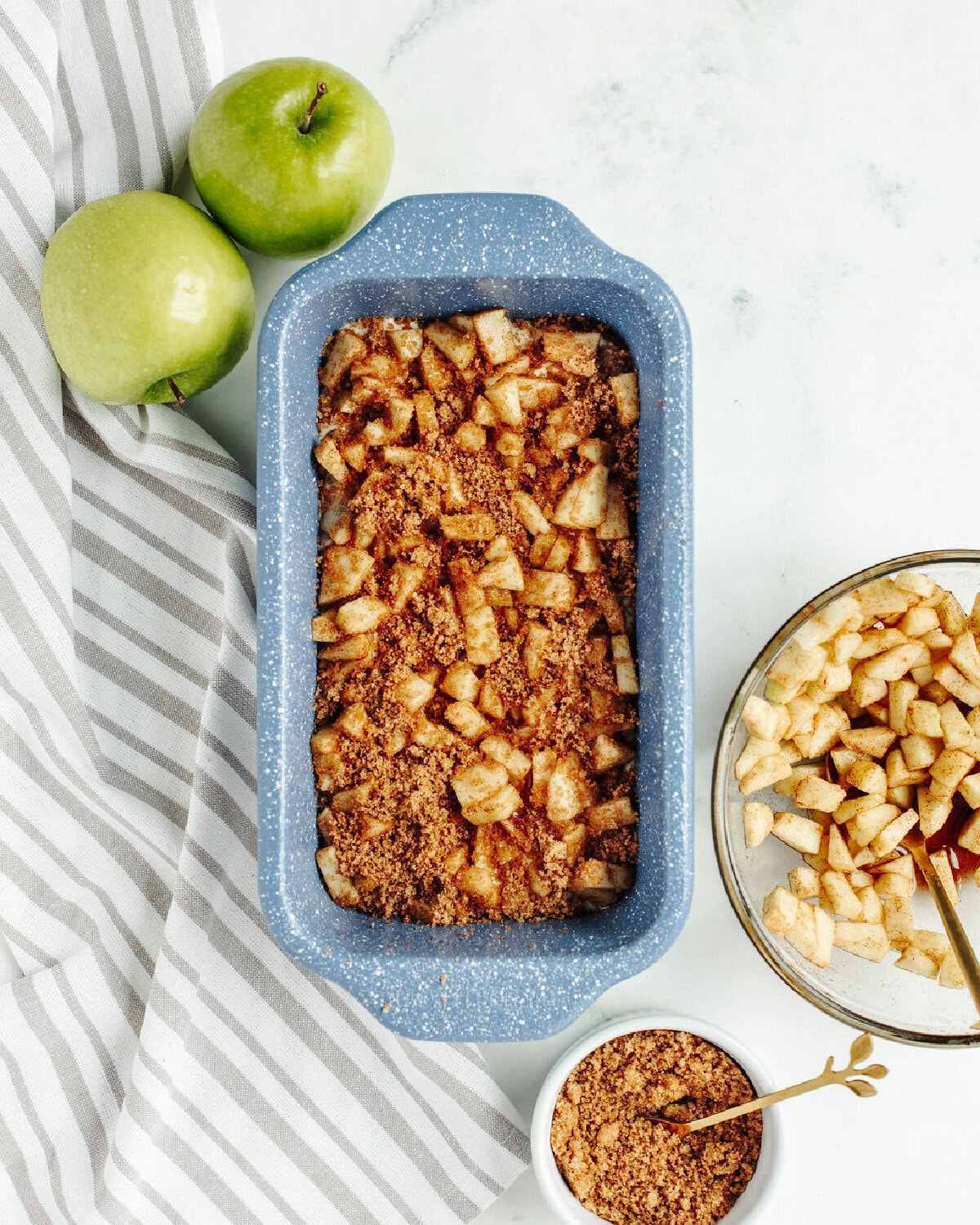 a cinnamon spiced apple mixture sprinkled over apple batter in a loaf pan.