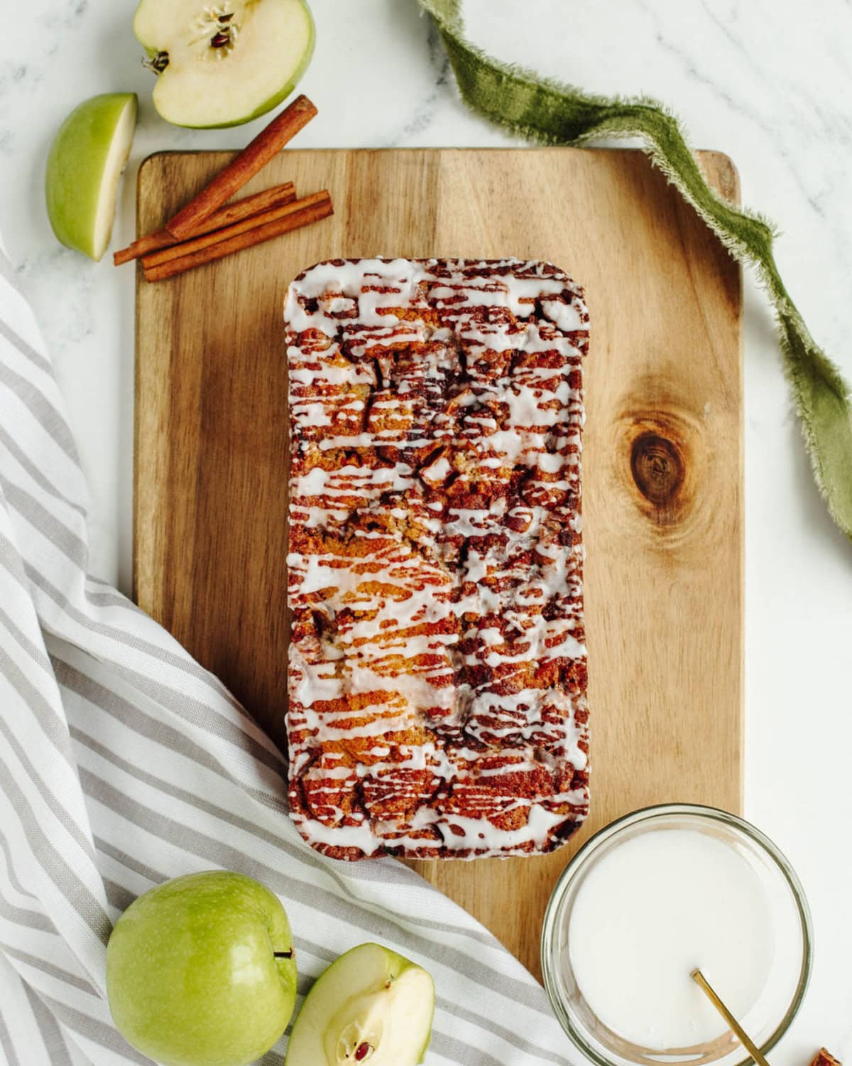 a baked loaf of easy apple fritter bread on a wood cutting board.