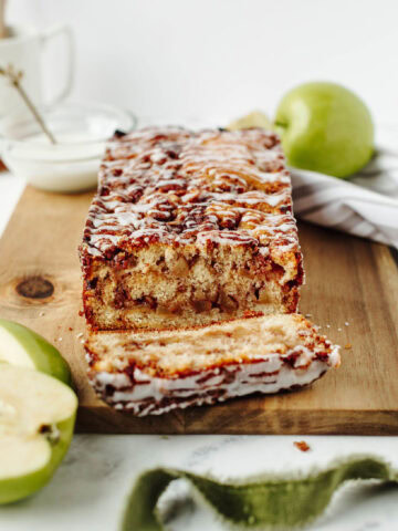 sliced apple fritter bread on a wood cutting board.