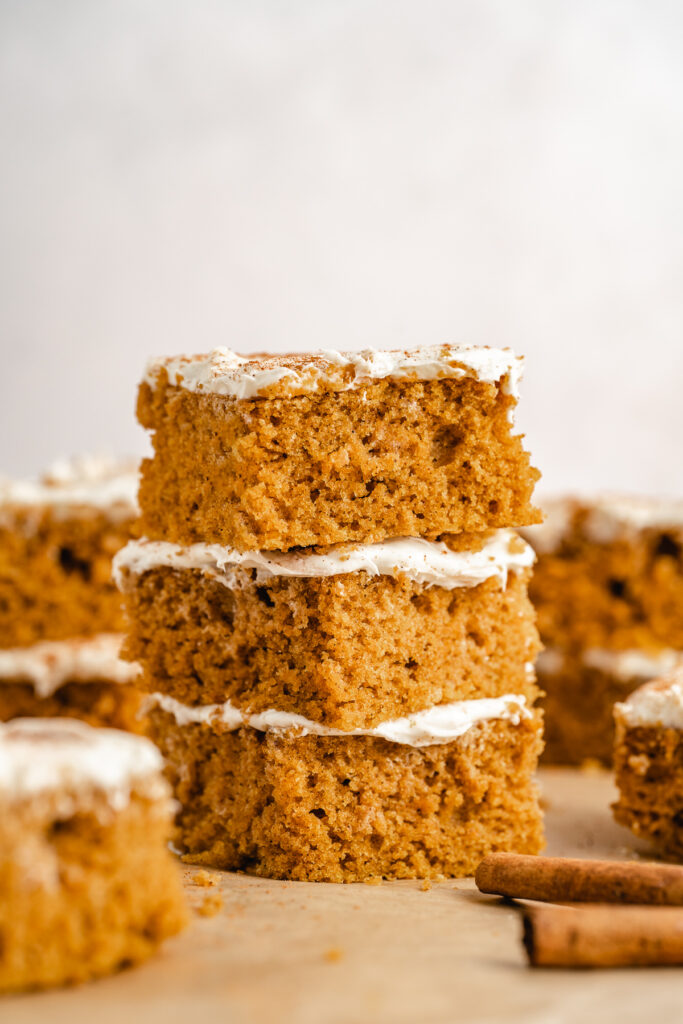 a stack of cut piece of pumpkin cake with cream cheese frosting
