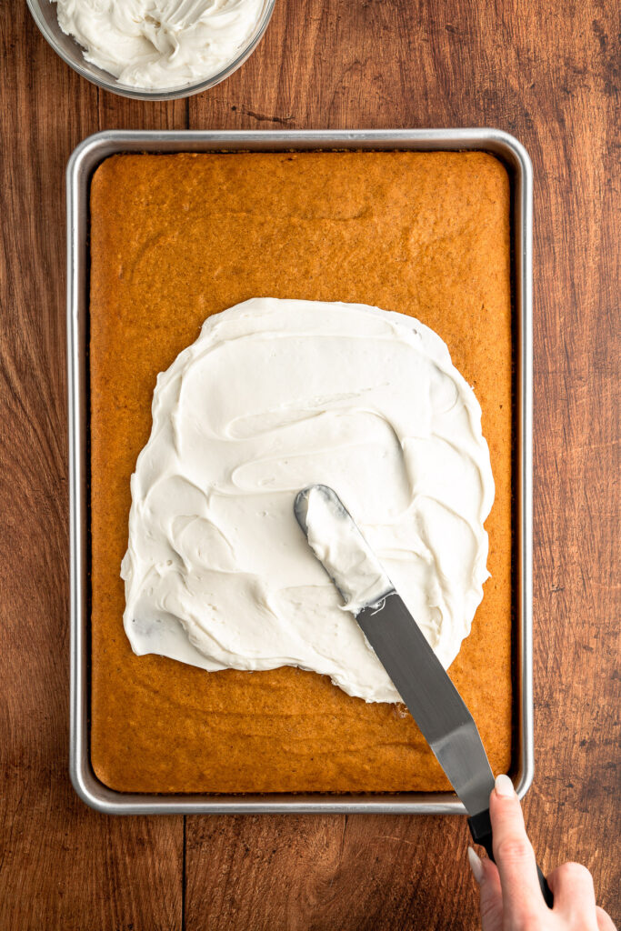 creamy cheese frosting getting spread over spice cake