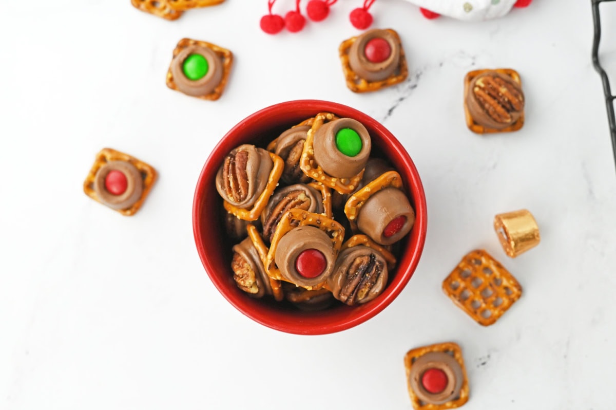 a red serving dish with christmas themed rolo pretzel treats.