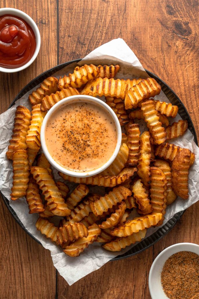 a platter of french fries with a side of ketchup and tangy comeback sauce