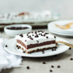 a slice of Chocolate Chip Cookie Dessert with Cool Whip on a white plate.