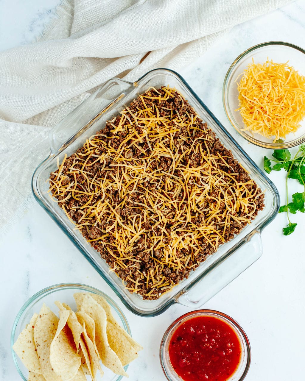 taco seasoned ground beef and shredded cheese on top of cooked macaroni shell pasta.
