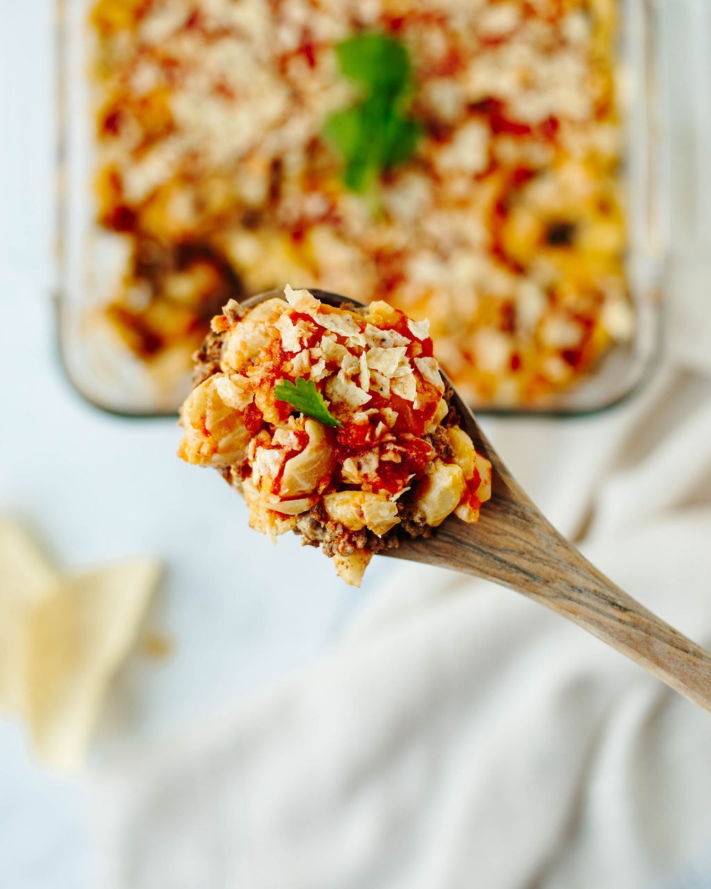 Close up of cheesy nacho bake recipe with pasta shells, ground beef, salsa, and melted cheese.