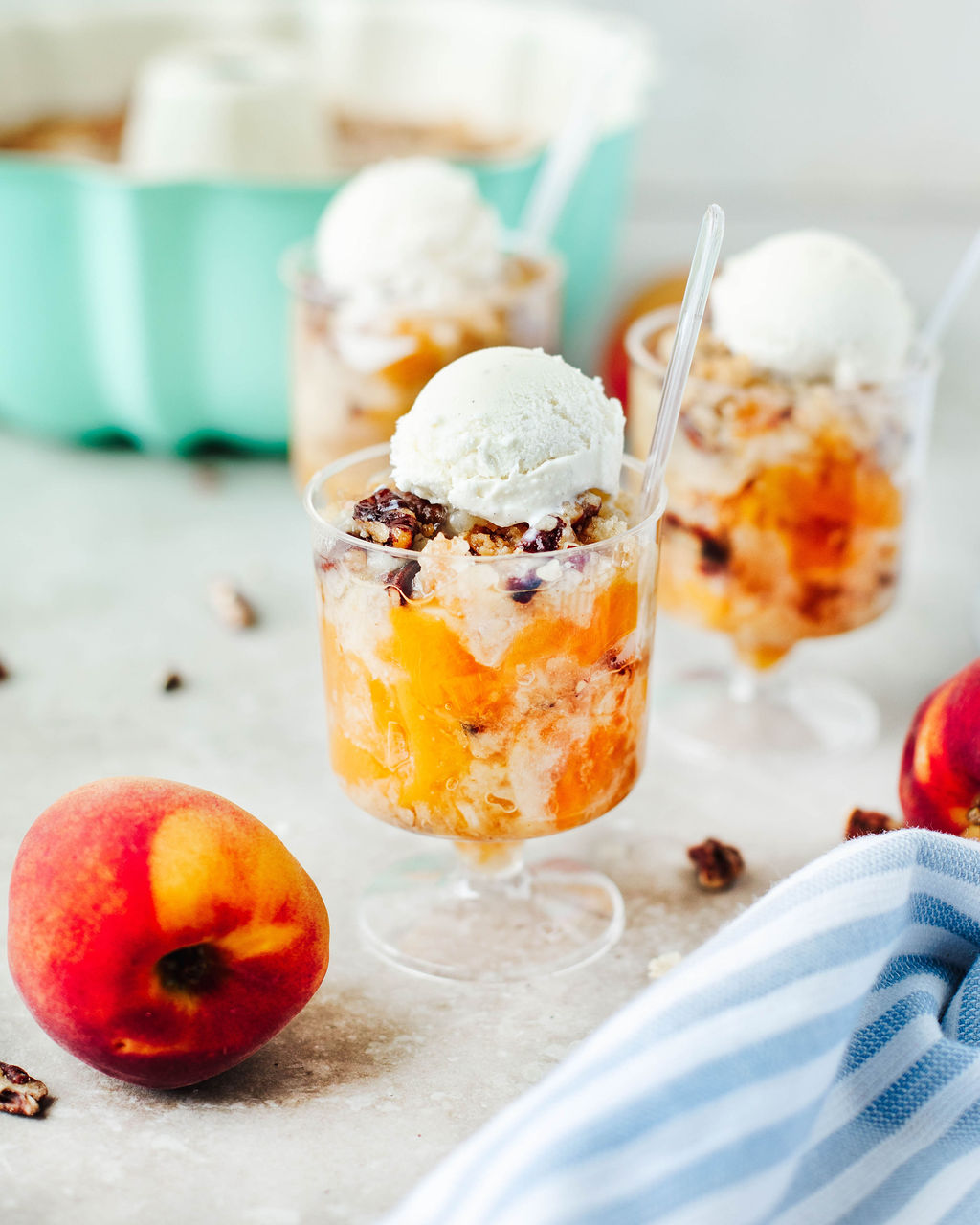 a scoop of Bisquick Peach Cobbler in a glass dish with ice cream.
