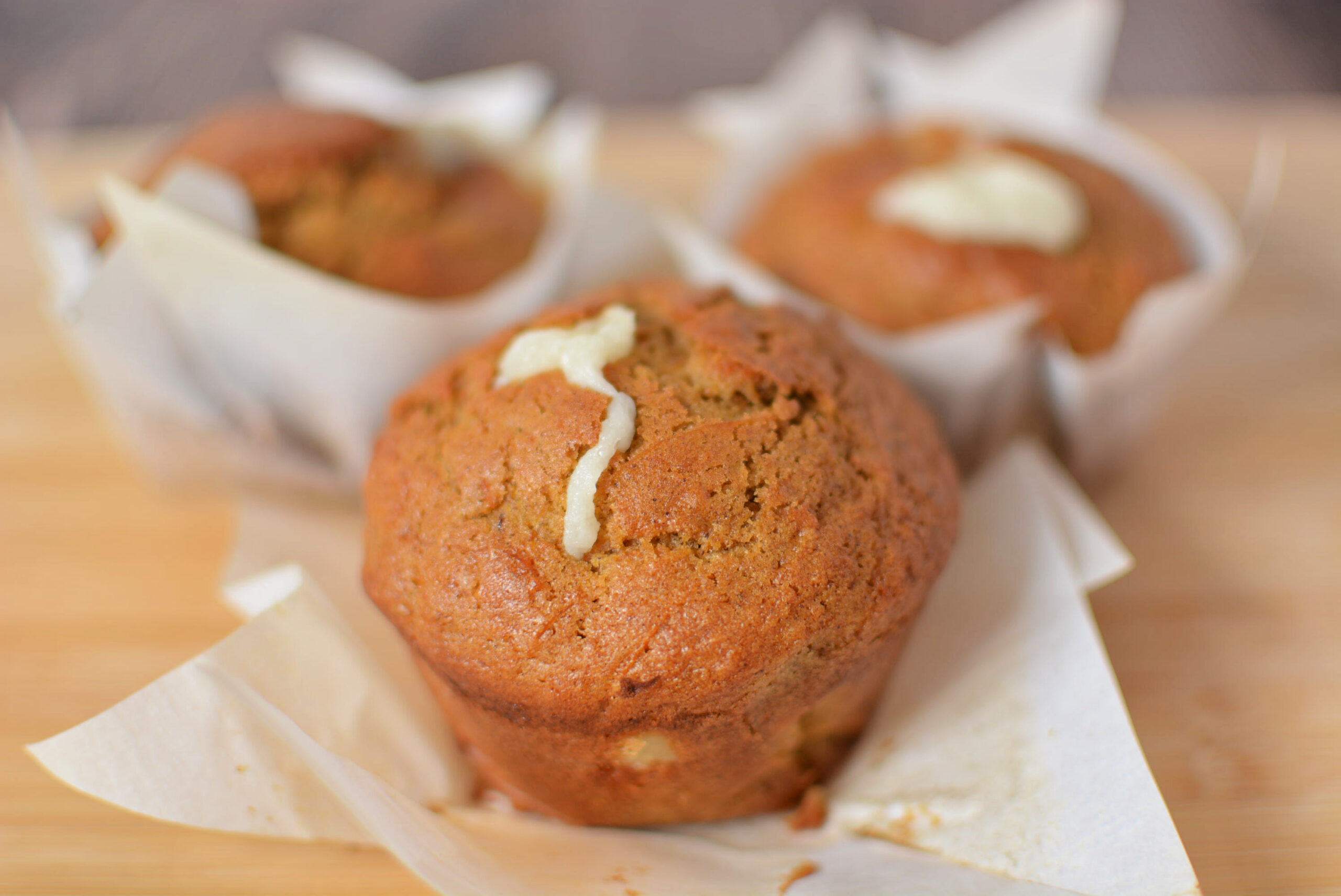 a carrot cake muffin with cream cheese filling on a white paper liner.