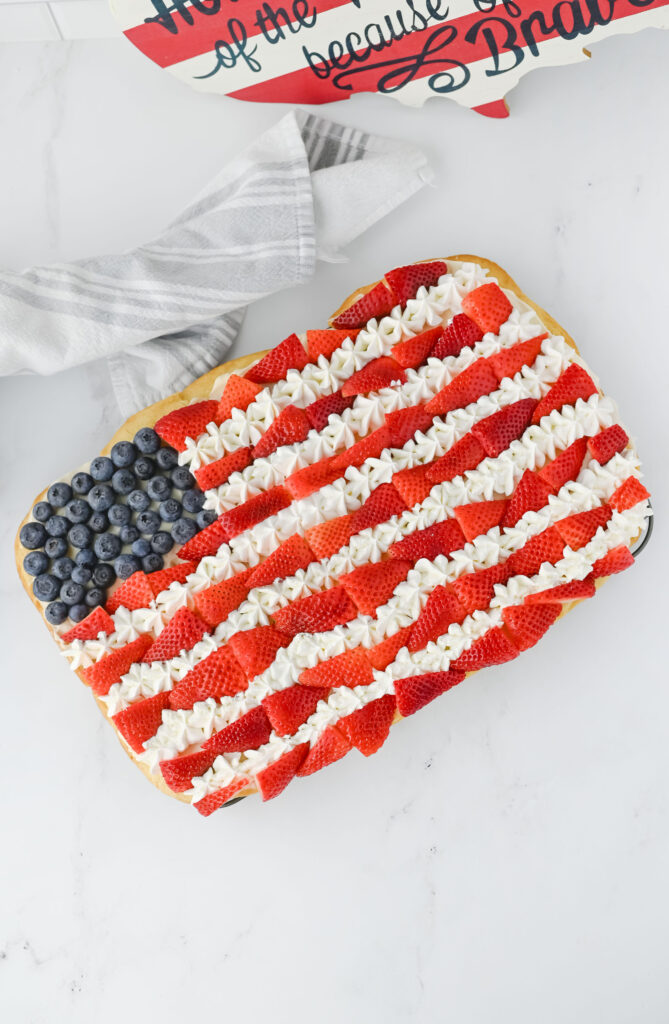 Crosta de biscoito de açúcar de pillsbury, cobertura de cream cheese e frutas frescas montadas para uma pizza de sobremesa.