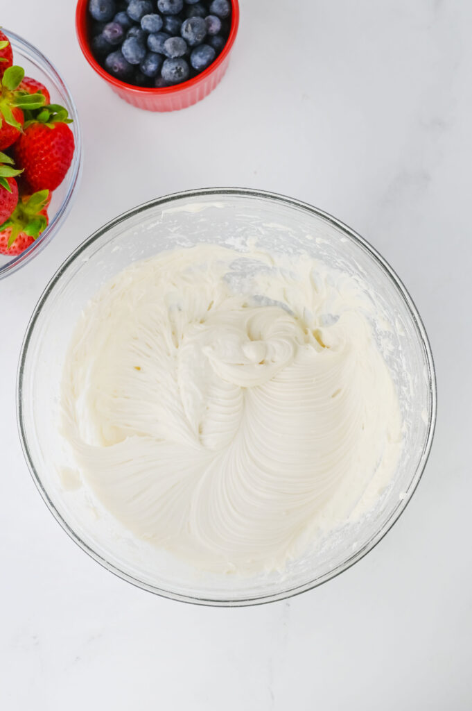 Creme de queijo e açúcar combinado em uma tigela de vidro.