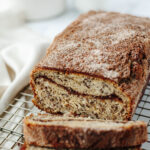 a loaf of snickerdoodle banana bread on a wire rack.