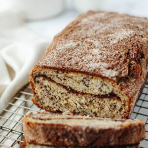 a loaf of snickerdoodle banana bread on a wire rack.