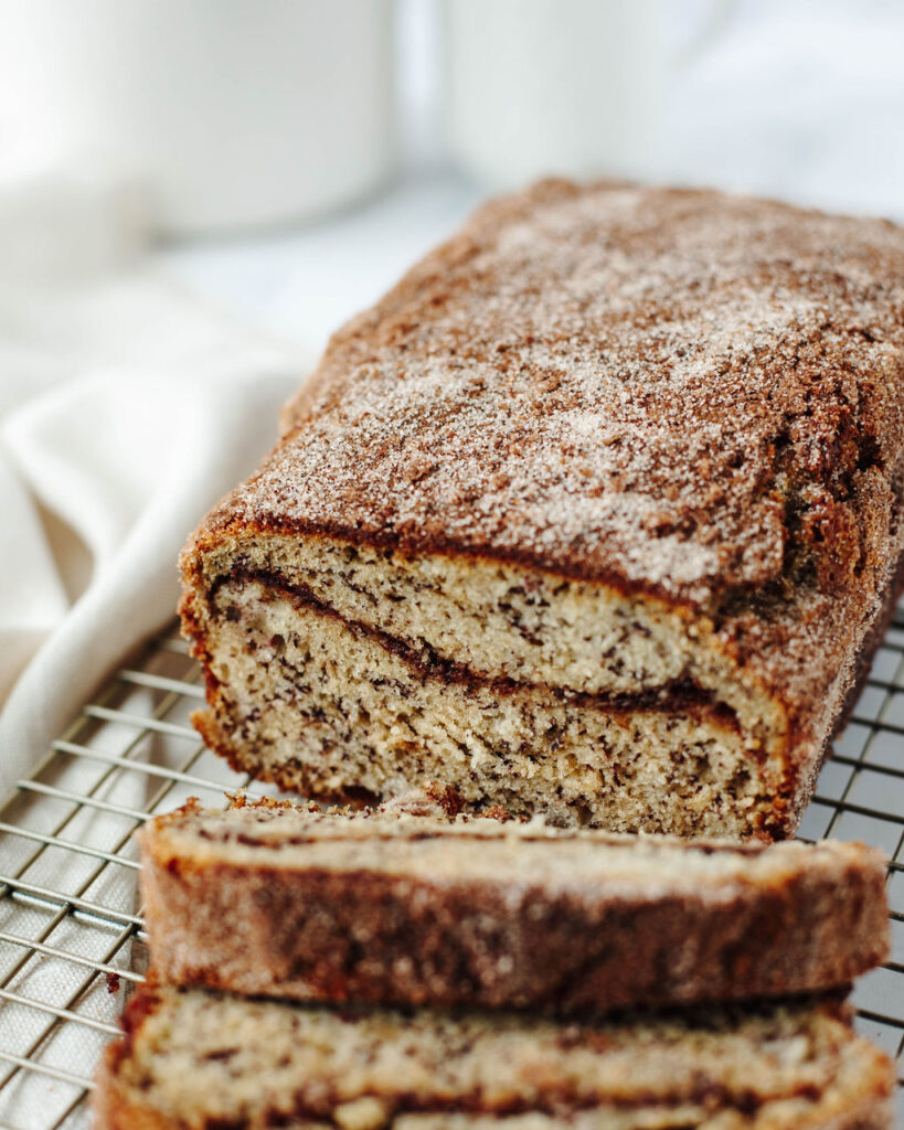 a loaf of snickerdoodle banana bread on a wire rack.