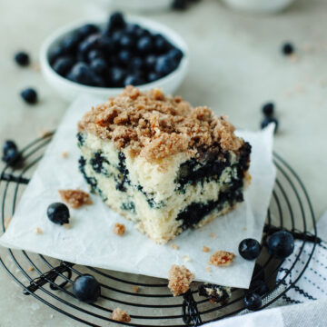 a slice of cake on a wire rack with fresh berries.