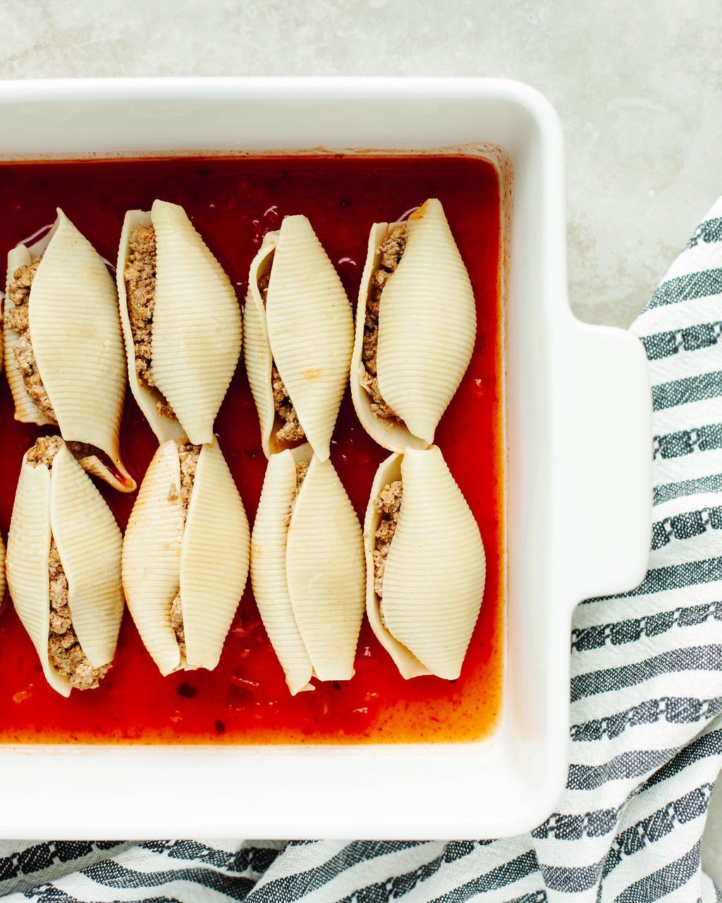 Jumbo pasta shells being filled with ground beef mixture for Mexican stuffed shells recipe.