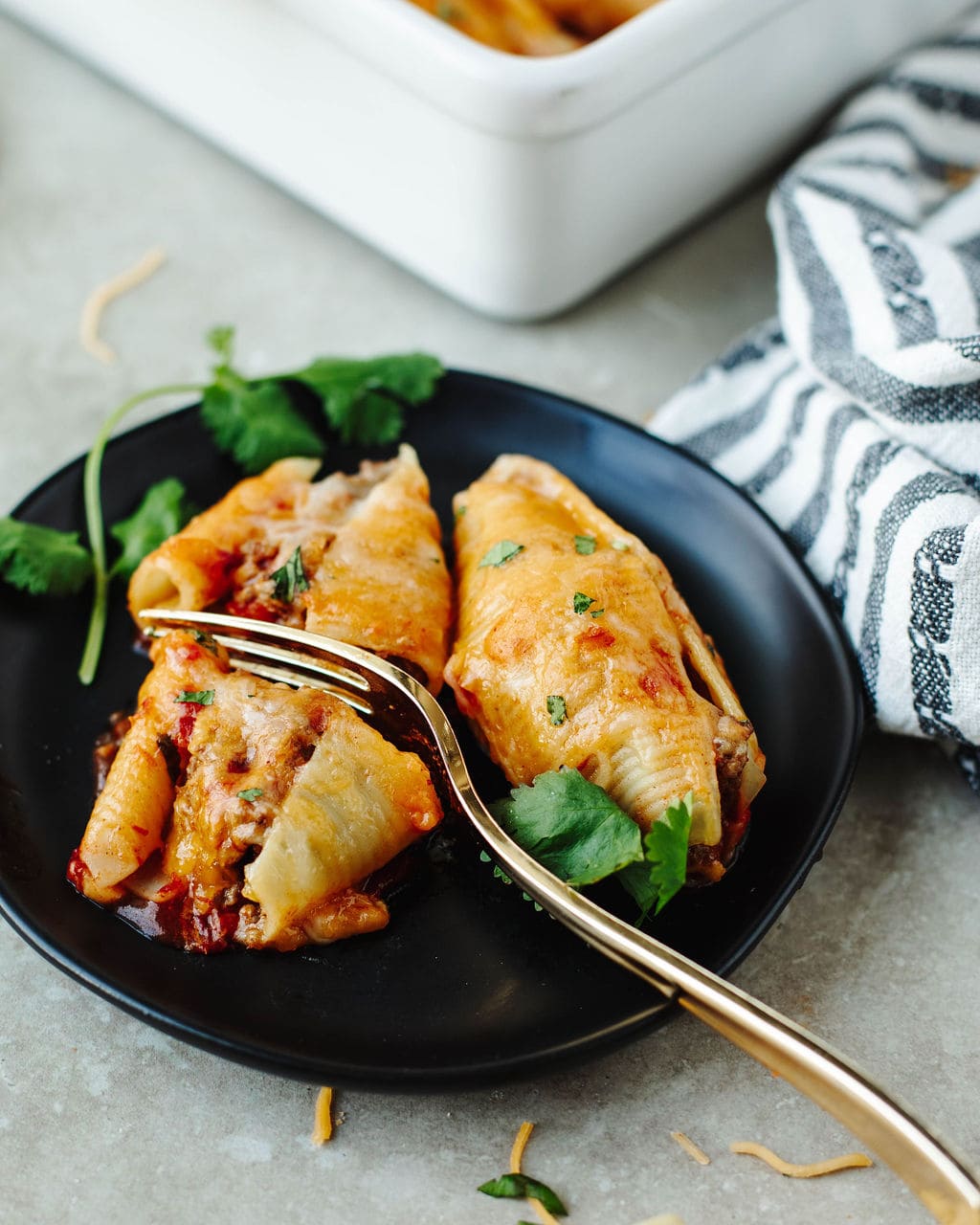 Plate of Mexican stuffed pasta shells served with fresh toppings.