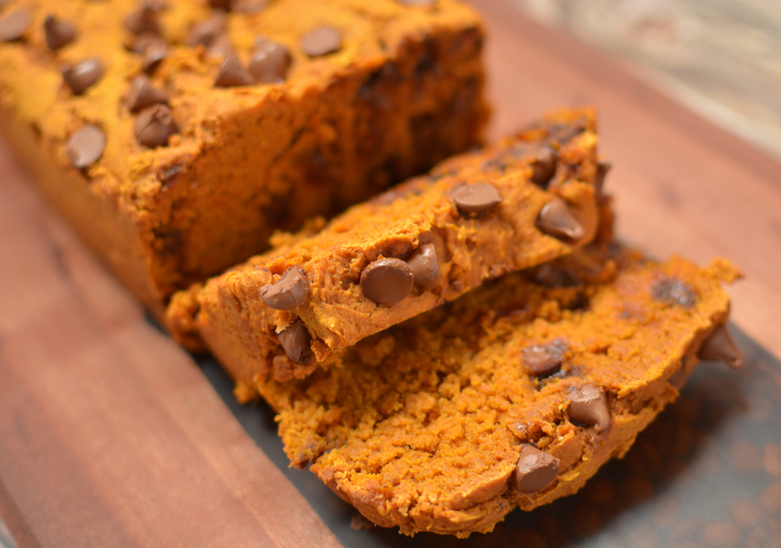 pumpkin chocolate chip bread sliced on a cutting board.