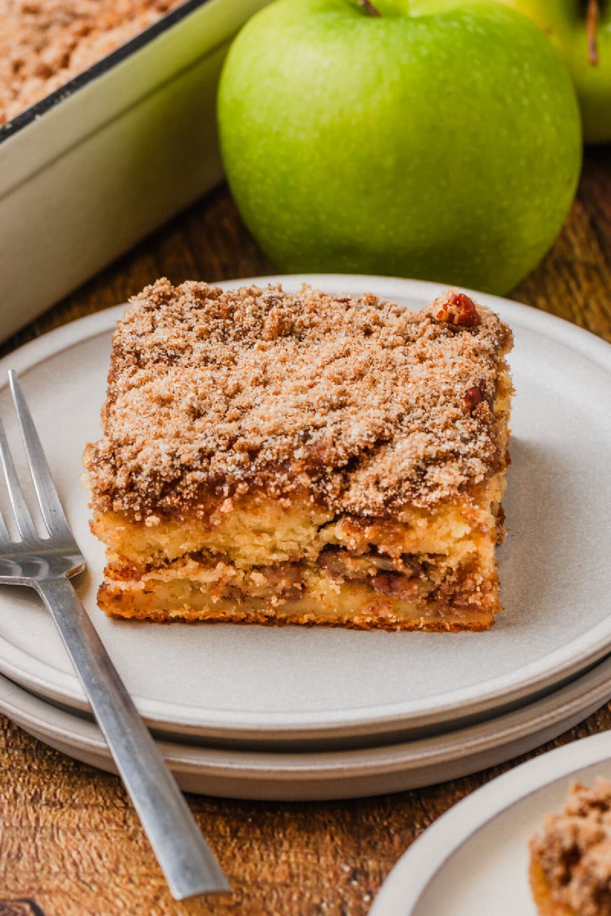 a slice of applesauce coffee cake on a white plate with a fork.