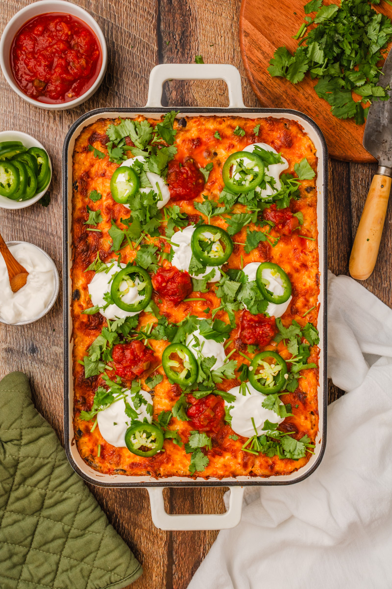 chicken taco casserole in a white pan with toppings.