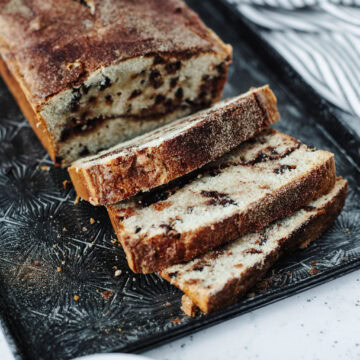 sliced Snickerdoodle Bread with mini chocolate chips throughout on a black cutting board.